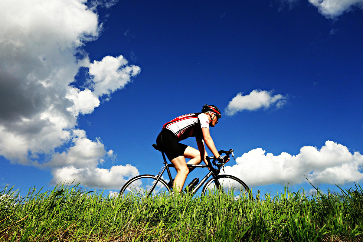 A cyclist riding a road bike under a bright sky