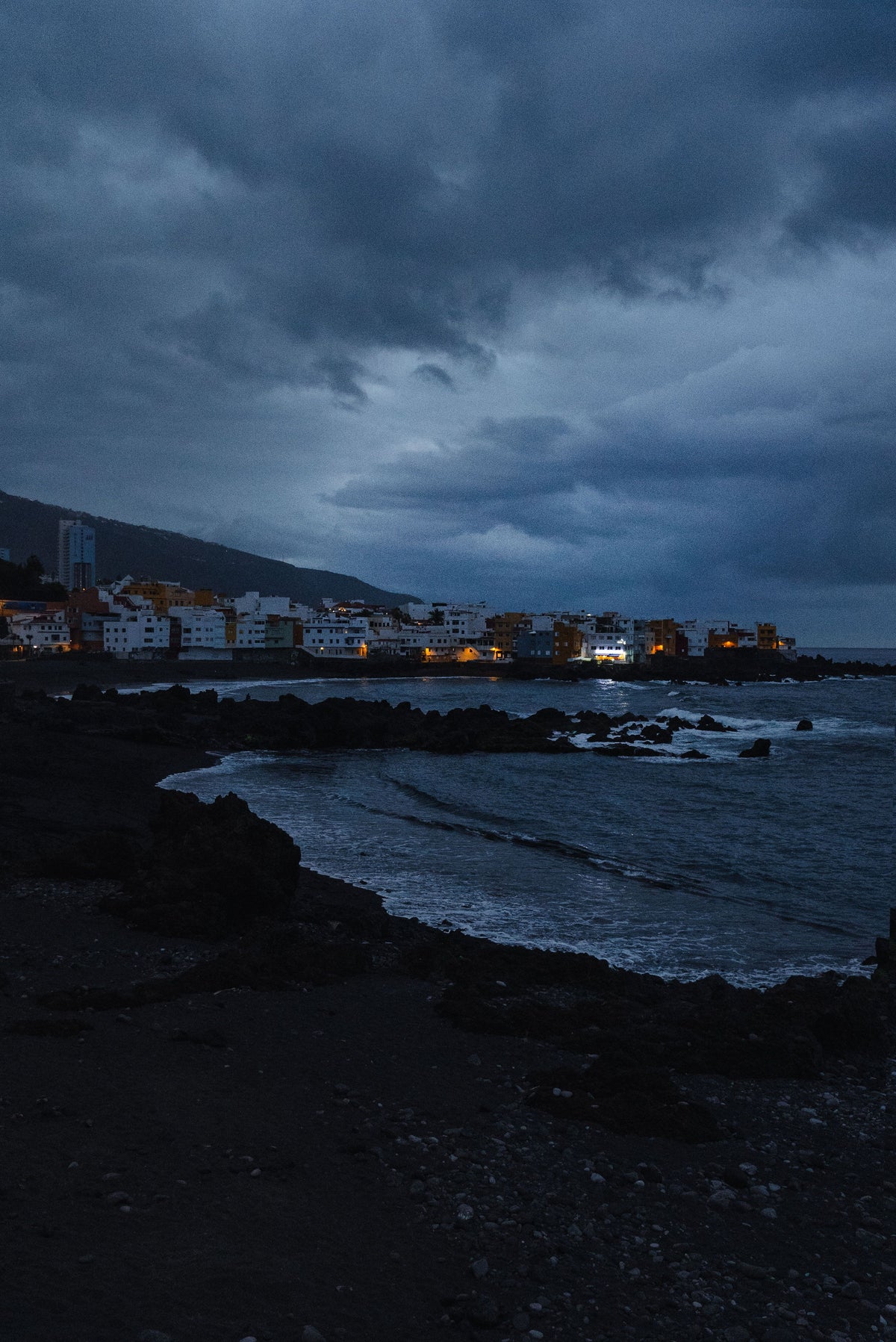 A coastal town under dramatic stormy rain clouds at dusk